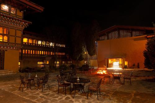 eine Gruppe von Tischen und Stühlen in einem Innenhof in der Nacht in der Unterkunft Hotel Olathang in Paro