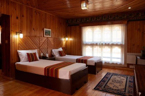 two beds in a room with wooden walls and wooden floors at Hotel Olathang in Paro