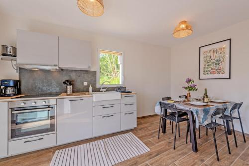 une cuisine avec des appareils blancs et une table avec des chaises dans l'établissement Toudig - Maison avec terrasse et jardin, à Plougastel-Daoulas