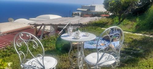 a table and chairs in the grass with a view of the ocean at villa lucia in Conca dei Marini