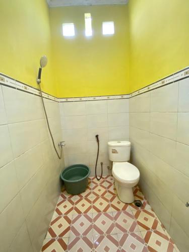 ein Badezimmer mit einem WC und einem grünen Eimer in der Unterkunft Ijen kingdom guest house in Tamansuruh