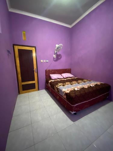 1 dormitorio con 1 cama en una habitación púrpura en Ijen kingdom guest house en Tamansuruh