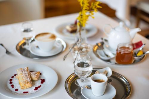 a table with plates of food and cups of coffee at Hotel Radun in Luhačovice