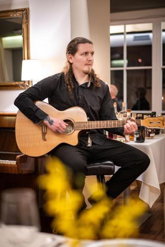 a man sitting in a chair playing a guitar at Hotel Radun in Luhačovice