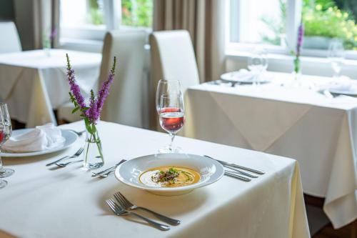 a table with a plate of food and a glass of wine at Hotel Radun in Luhačovice