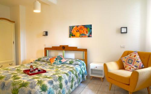 a bedroom with a bed and a chair at Flowery Inn Villa in Alghero