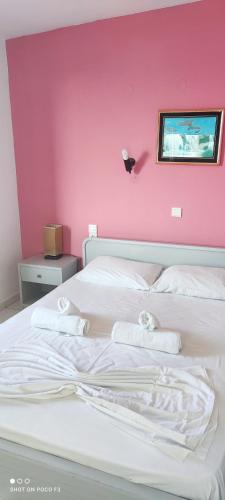 a bedroom with two beds and a pink wall at Koralli Sea View Hotel in Kato Achaia