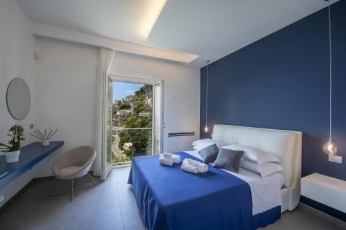ein blau-weißes Schlafzimmer mit einem Bett und einem Fenster in der Unterkunft Luxury Villa Donna Rachele in Amalfi