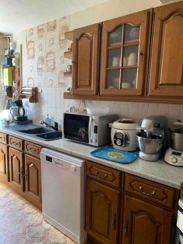 - une cuisine avec des placards en bois et un four micro-ondes blanc dans l'établissement Agréable ancienne maison de ville, au Château-dʼOléron