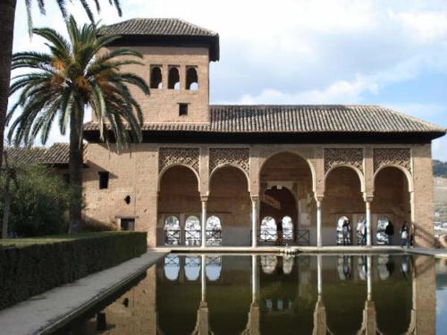 グラナダにあるcasa carmen alhambraの水の隣のヤシの木がある建物