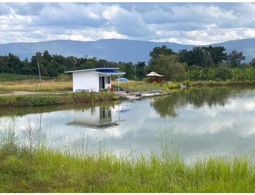 ein kleines weißes Gebäude neben einem Wasserkörper in der Unterkunft Chaiyaphum Monster Fishing Resort in Ban Huai Kum