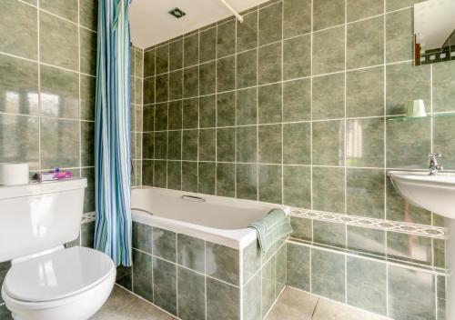 a bathroom with a toilet and a tub and a sink at 2 Derw Cottages in Trefeglwys