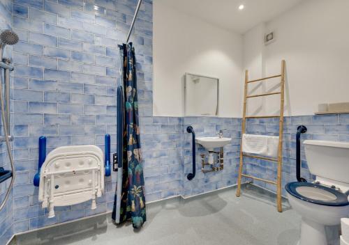 a blue tiled bathroom with a toilet and a sink at Malt Hall in Llanrhidian