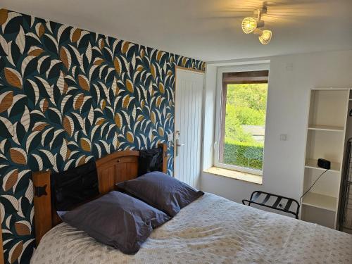 a bedroom with a bed and a wall with a leafy wallpaper at La kaz à Cisco - Maison indépendante avec terrain in Nouzonville