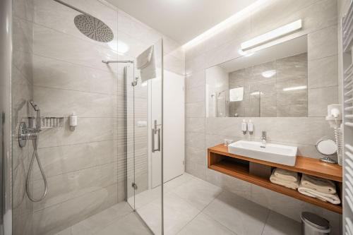 a white bathroom with a sink and a shower at Vila EVA in Luhačovice