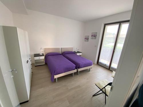 ein Schlafzimmer mit einem lila Bett und einem Fenster in der Unterkunft Casa Martinelli in Nago-Torbole