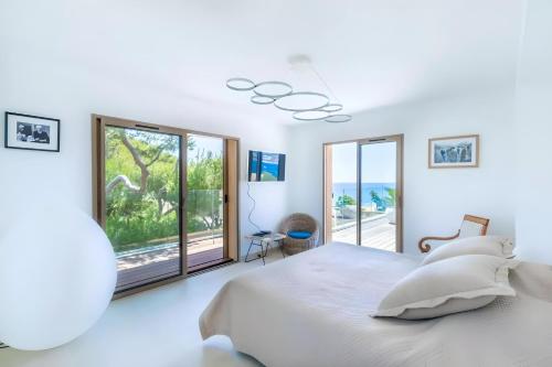 une chambre blanche avec un lit et une grande fenêtre dans l'établissement Villa Abalone - Propriété d'Exception, à Sanary-sur-Mer