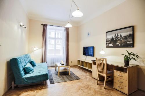 a living room with a desk and a blue couch at Accommodation Smečky 14 in Prague