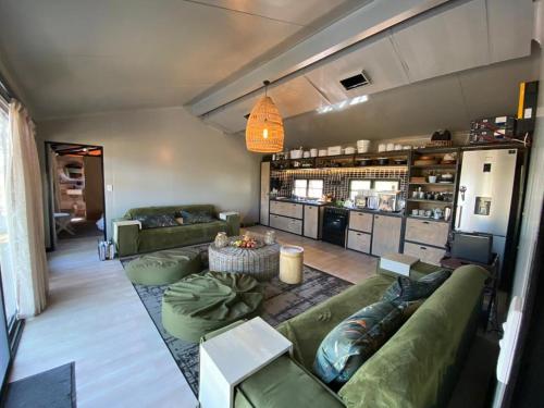 ein Wohnzimmer mit grünen Sofas und einem Tisch in der Unterkunft Kameeldoring Glamping Namibia 
