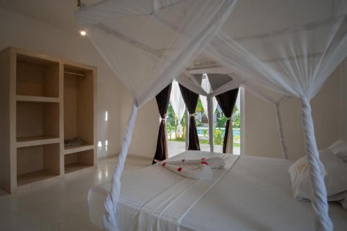 1 dormitorio con cama blanca con dosel y ventana en Mwezi - Maisha Resort, en Watamu