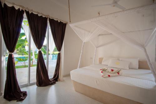 a bedroom with a white bed and a large window at Mwezi - Maisha Resort in Watamu