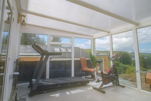a gym with a treadmill and a chair in a room with windows at Luxury 4 Bedroom Cottage With Stunning Views Near Fairy Pools! Open / Bookable in Carbost