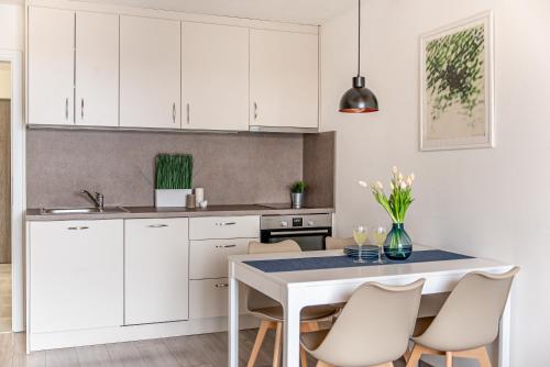 a kitchen with white cabinets and a table with chairs at Lipno Korzo Residence in Lipno nad Vltavou