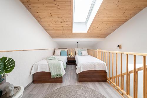 two beds in a attic room with a skylight at Lipno Korzo Residence in Lipno nad Vltavou