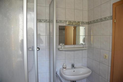 La salle de bains blanche est pourvue d'un lavabo et d'une douche. dans l'établissement Stiftsgasthof Hochburg, à Hochburg-Ach