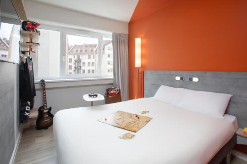a bedroom with a white bed with an orange wall at Ibis Budget Strasbourg Centre Republique in Strasbourg