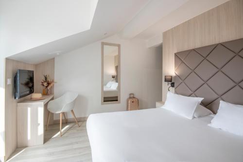a bedroom with a large white bed and a television at GOLDEN TULIP CANNES HOTEL de PARIS in Cannes