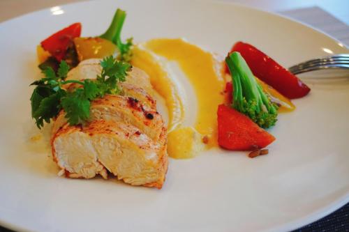 a white plate with a piece of meat and vegetables at Escale International Hotel in Djibouti