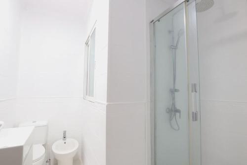 ein weißes Bad mit einer Dusche und einem Waschbecken in der Unterkunft Notel Club - Corazón Urbano in Santander