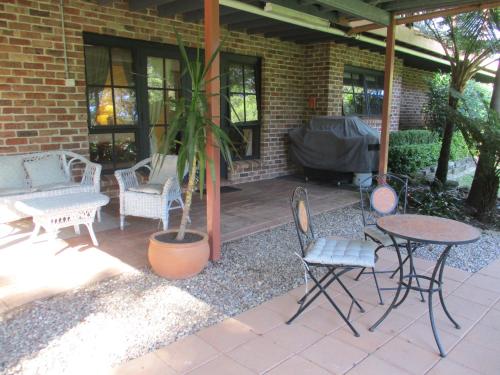 a patio with a table and chairs and a potted plant at Warriwul Farmland Rural Retreat BnB, Curramore/Jamberoo in Jamberoo