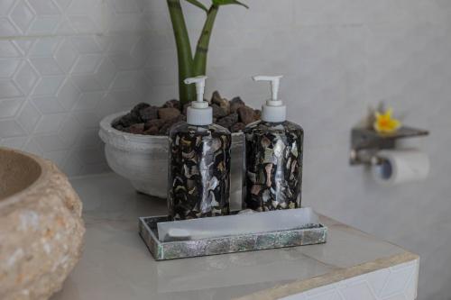 two bottles on a counter in a bathroom with a plant at Radjes Bungalow Nusa Penida in Nusa Penida
