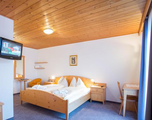 a bedroom with a bed with a wooden ceiling at Good Life Hotel Zirm in Obereggen