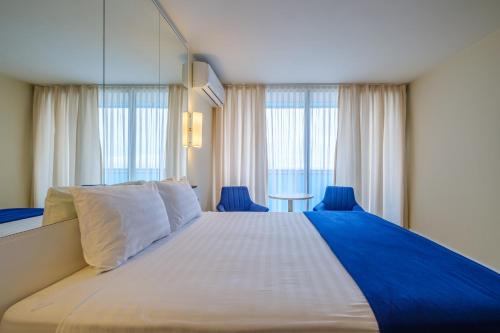a bedroom with a large bed with blue chairs and windows at Orbi City Hotel Official in Batumi