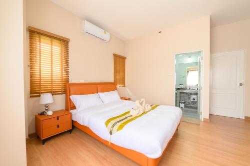 a bedroom with a large white bed with a wooden headboard at ็Hill Lake Villa - ฮิลล์เลค วิลล่า in Ban Ton Ngiu