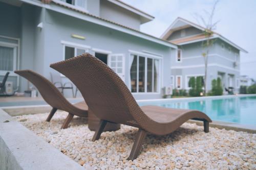 a couple of chairs sitting next to a swimming pool at ็Hill Lake Villa - ฮิลล์เลค วิลล่า in Ban Ton Ngiu