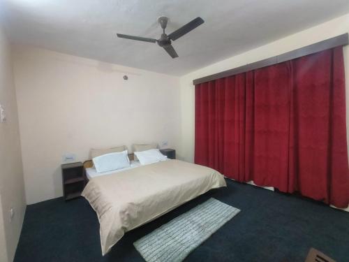 a bedroom with a bed with a ceiling fan at The Kailasha Homestay in Nagar