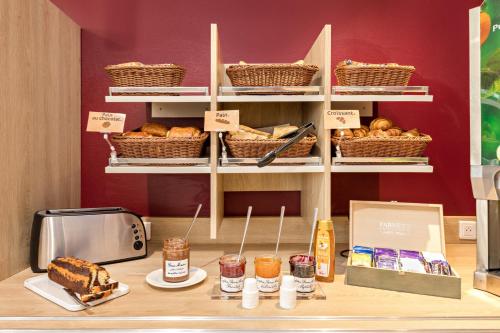 Un mostrador de panadería con pasteles, tostadora y pan. en Ace Hôtel Salon de Provence, en Salon-de-Provence
