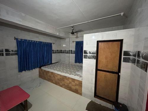 een kleine kamer met een bed en een blauw gordijn bij Tulsi Paradise Resort in Nirmal
