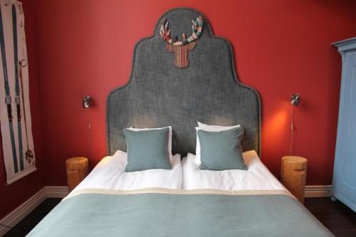a bed with a large headboard in a red bedroom at Olarsgården Hotell in Lindvallen
