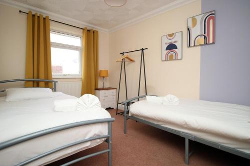 two beds in a room with a window at 3 Bed with Free Parking - Merriotts 1 by Tŷ SA in Newport