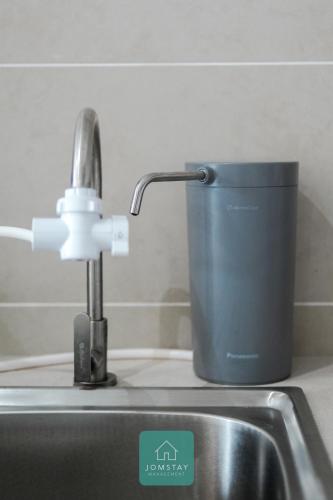 a cup sitting next to a kitchen sink with a faucet at JOMSTAY Sunway Onsen Suites Ipoh - Lost World of Tambun Ipoh Waterpark in Tambun