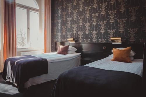 two beds sitting in a room with a window at Stadshotellet Lidköping in Lidköping