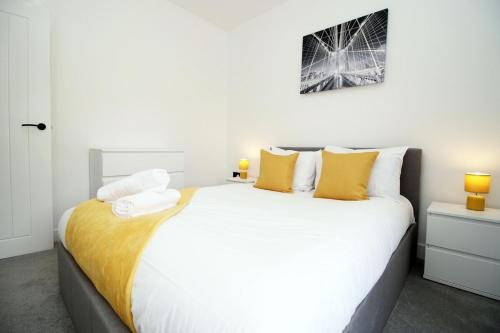 a bedroom with a large white bed with yellow pillows at 3 Bedroom House in Mountain Ash Cynon View by TŷSA in Quakers Yard