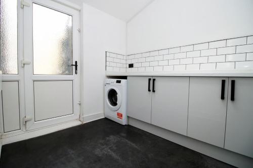 a white kitchen with a washing machine and a window at 3 Bedroom House in Mountain Ash Cynon View by TŷSA in Quakers Yard