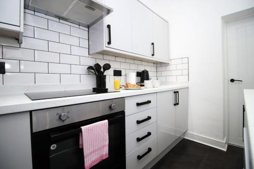 a white kitchen with a sink and a stove at 3 Bedroom House in Mountain Ash Cynon View by TŷSA in Quakers Yard