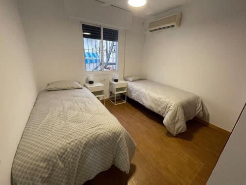 twee bedden in een kleine kamer met een raam bij Dos hermanas - Feel at home in Dos Hermanas